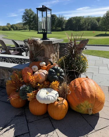 A pumpkin and gourd arrangement built around a stone lamp post on a patio