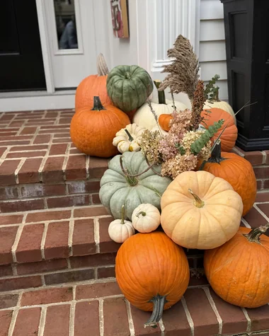 Pumpkins and gourds cascading down brick steps beside a black planter