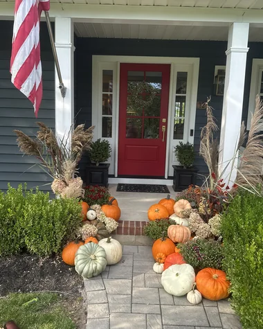 Pumpkins, gourds and grasses along the walk to a red front door