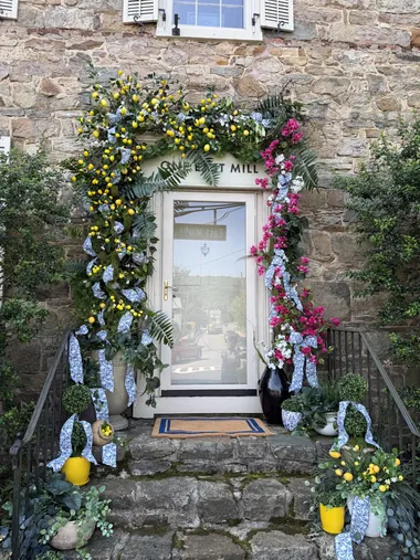 A stone doorway with a spring floral arch in pinks and purples