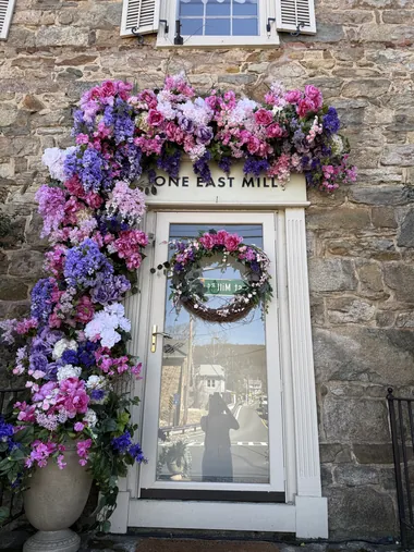 A stone doorway with a citrus and ribbon arch in yellows and blues