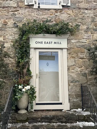A stone doorway with a white hydrangea and greenery arch