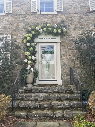 A stone doorway with a restrained winter greenery arch and a stone urn