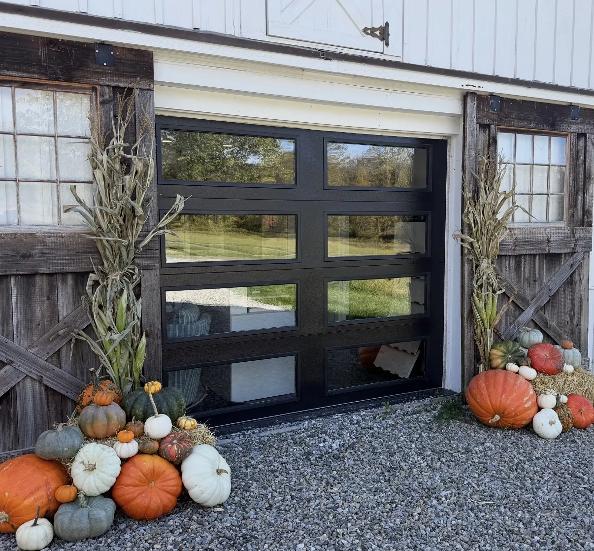 Two cornstalk bundles flanking a doorway with pumpkin clusters at the base